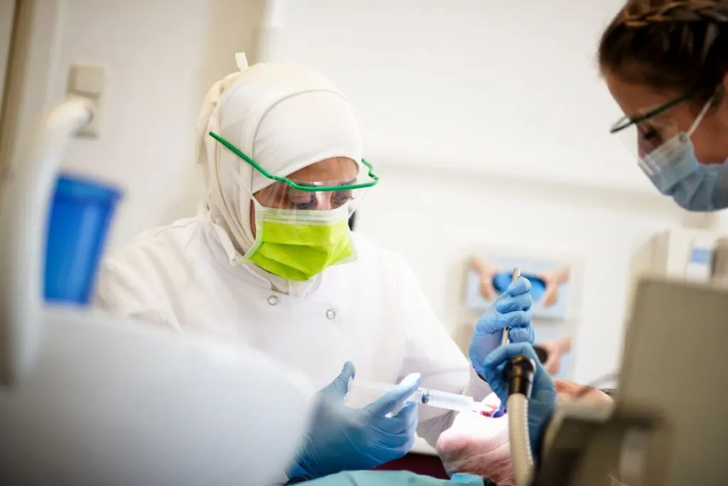 Mondhygiënist met spatbril aan het werk